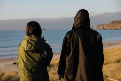 Koudwaterzwemmer gehuld in een waterdichte, met fleece gevoerde omkleedjas op een winters strand