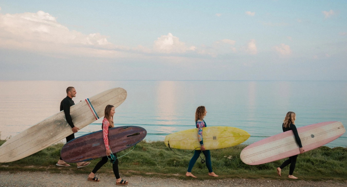 Surfers in zomerwetsuits op weg het water in