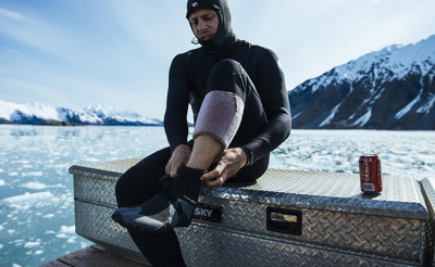 Surfer in een wetsuit draagt zijn surfboard over het strand
