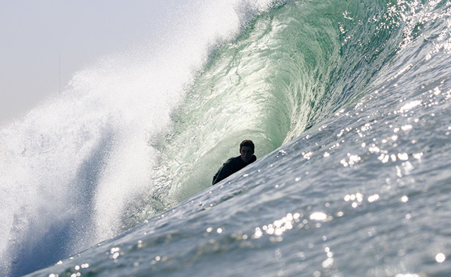 surfer die een wetsuit met borstrits aantrekt