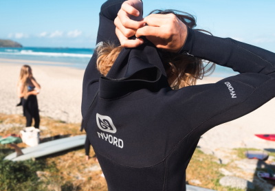 Surfer putting on a chest-zip wetsuit