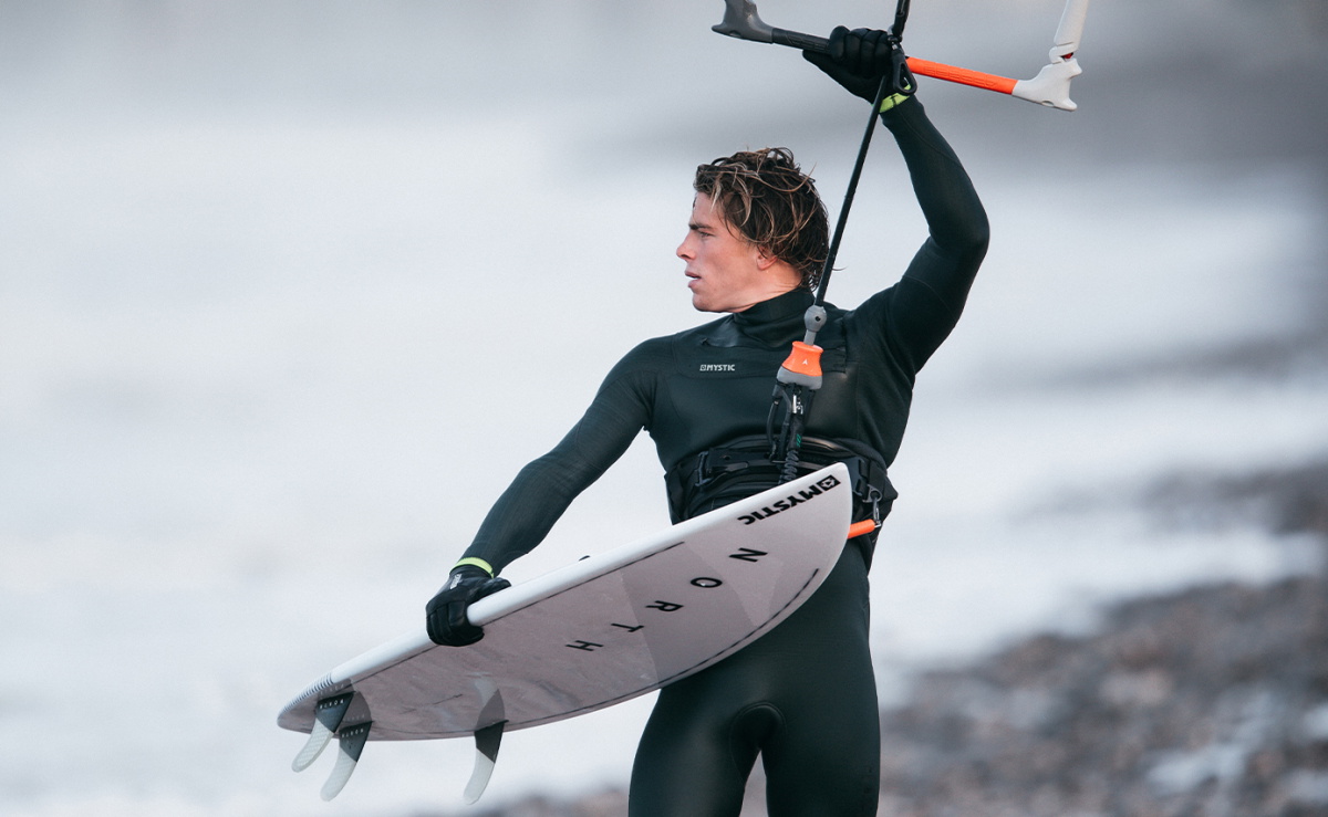 Riders van het Mystic-team in hun wetsuits uit de wintercollectie 20/21 op het strand