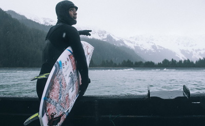 Surfer met wetsuitschoenen, handschoenen en cap