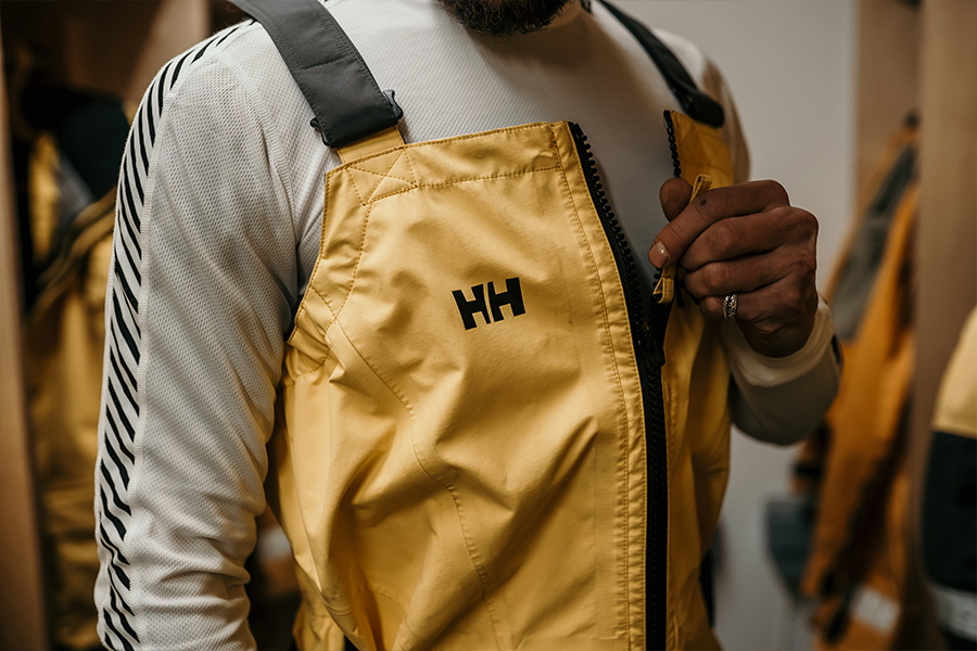 Close-up of a mustard yellow sailing jacket with the Helly Hansen logo on the chest