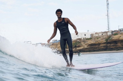 Surfer in een mouwloos Nyord Solu Long Jane wetsuit op een zomers strand