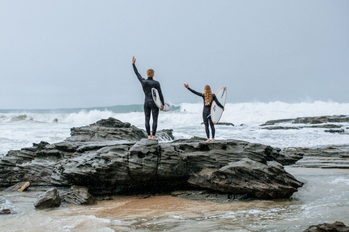 Surfer in een Rip Curl Trad wetsuit loopt met zijn board het water in